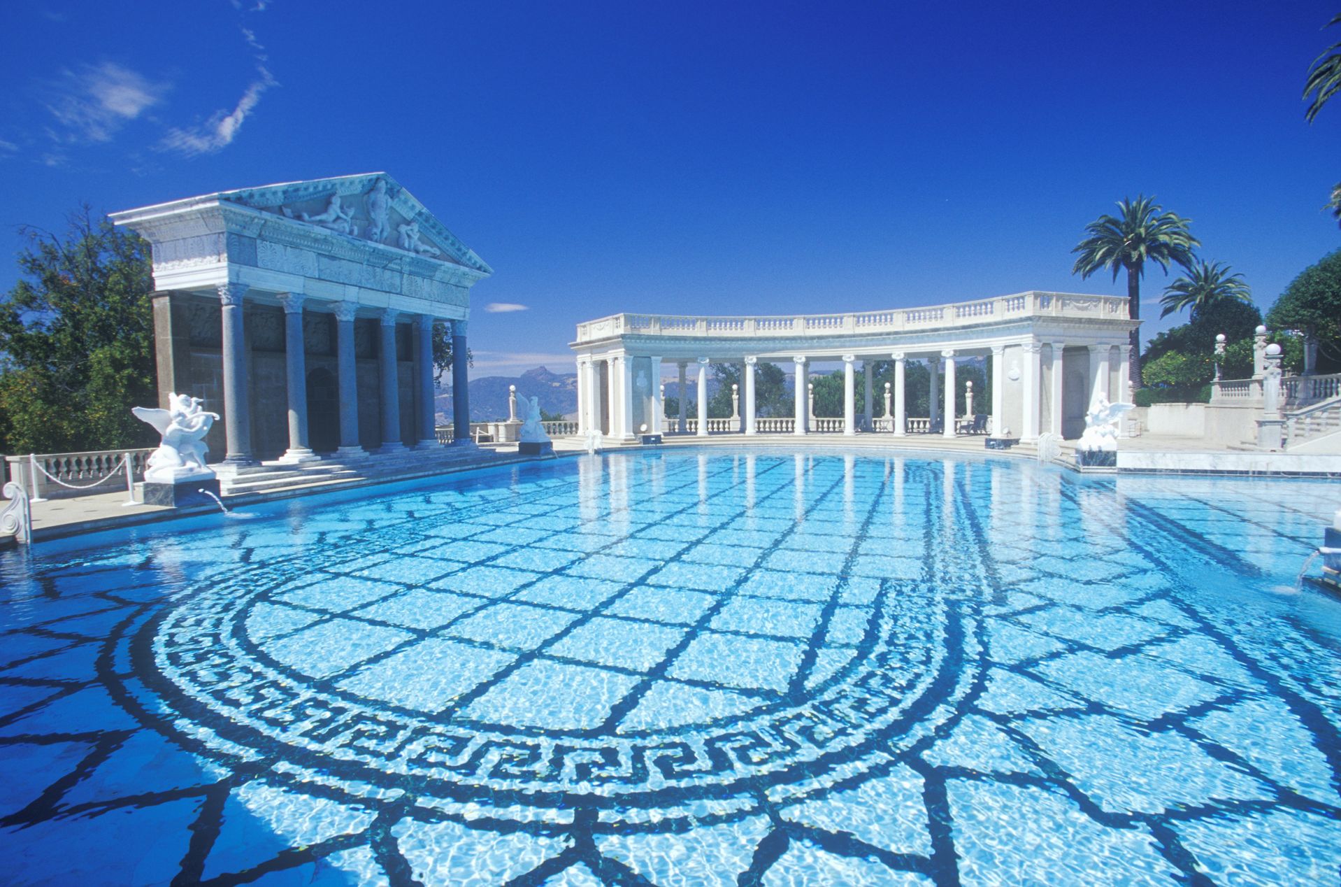 A Large Pool Of Water With Hearst Castle In The Background