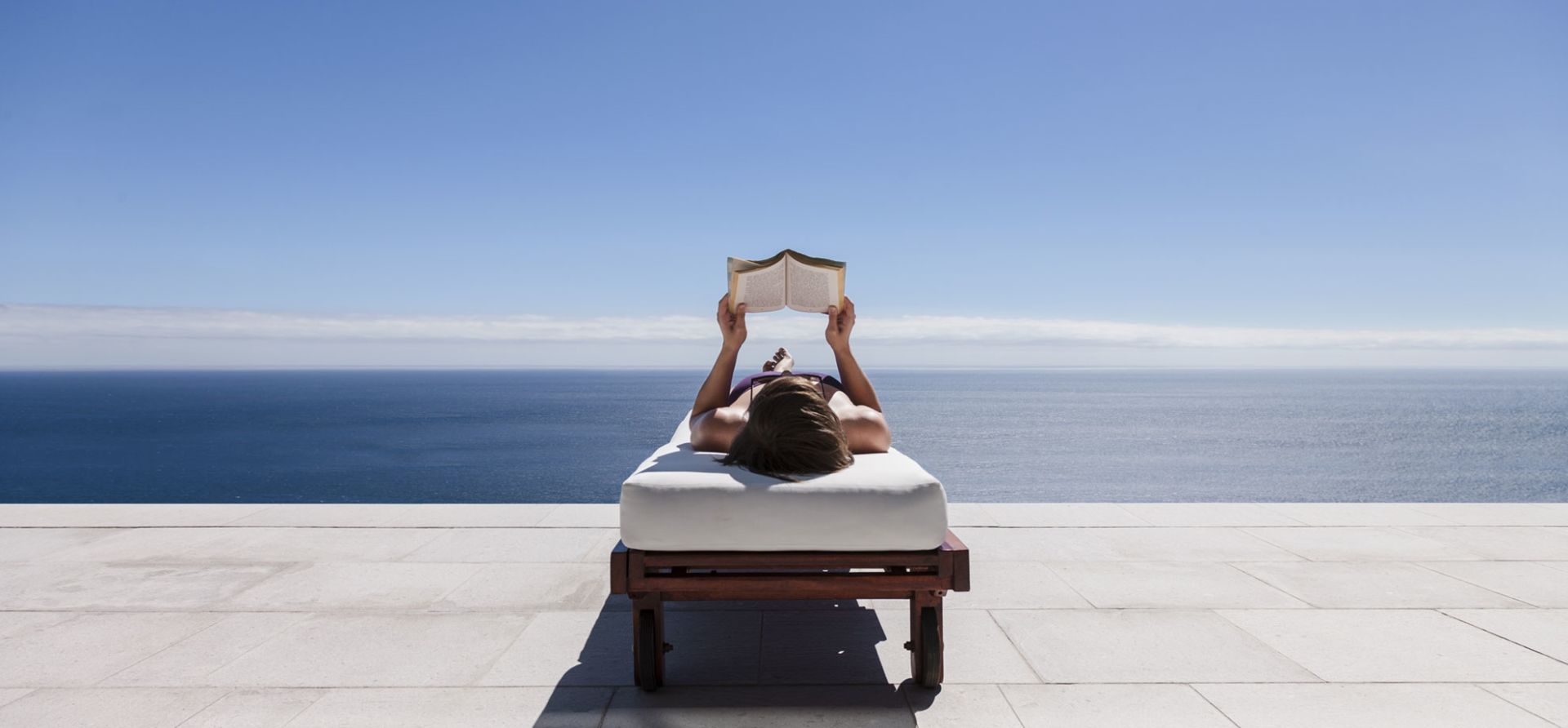 A Person Reading A Book Laying In A Pool Chair
